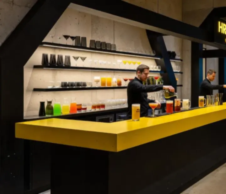 Neo‑brutalistický bar v restauraci Brnoriva uprostřed prostoru, připravený na večerní programy.
